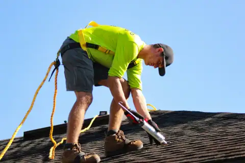 A Ridgeline roofer tied off on a shingle roof