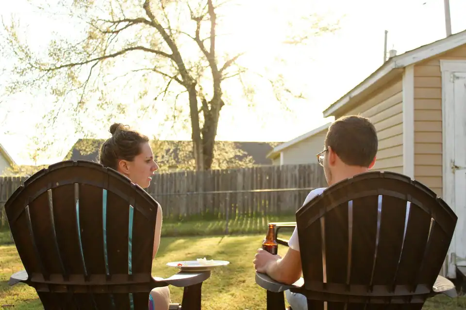A couple relaxing in Adirondack chairs in their backyard at golden hour